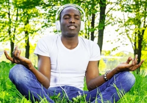 Young african american man in white shirt listens music in a park
