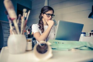Young woman sitting at desk looking at laptop