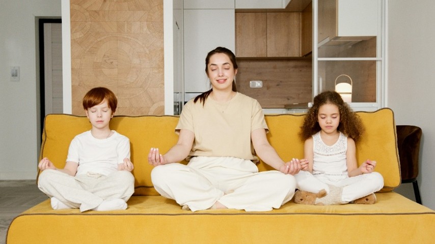 Mother and children meditating seated on couch